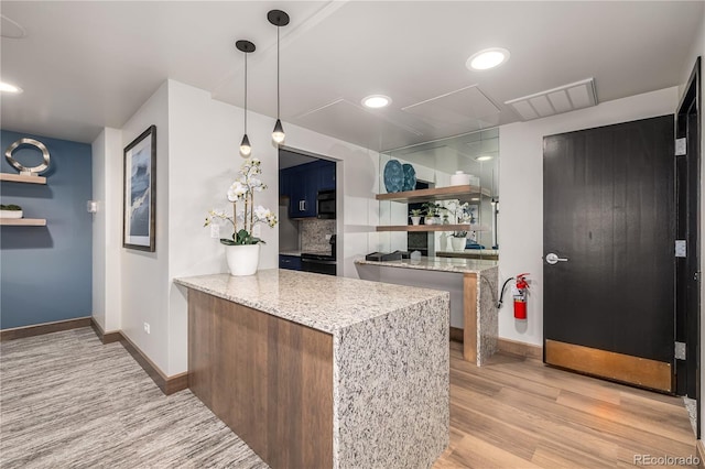 kitchen featuring decorative light fixtures, kitchen peninsula, decorative backsplash, light wood-type flooring, and light stone counters