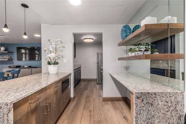 kitchen featuring light hardwood / wood-style flooring, built in microwave, light stone counters, and decorative light fixtures