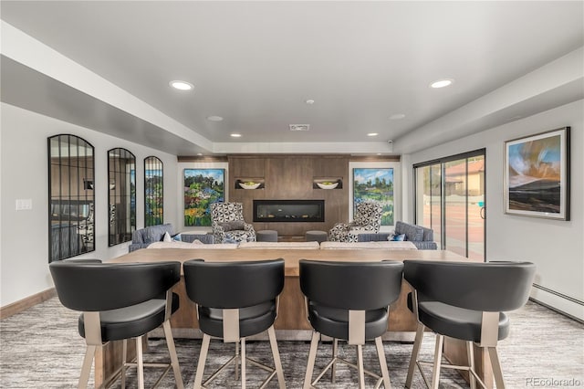 kitchen featuring a kitchen bar, a baseboard heating unit, and a fireplace