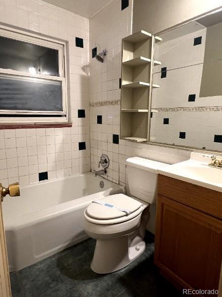 527 S Bryant St, Denver, CO 80219 - full bath with tile walls, vanity, tile patterned flooring, and washtub / shower combination