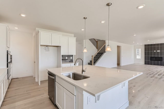 kitchen with white cabinets, an island with sink, hanging light fixtures, and sink