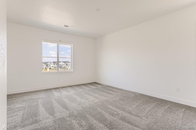 empty room featuring visible vents, baseboards, and carpet