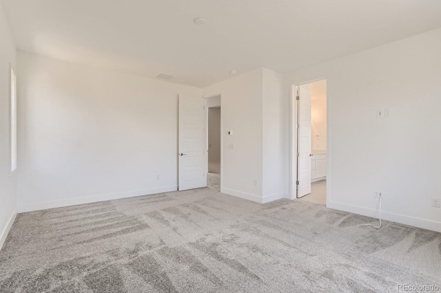 unfurnished room with baseboards and light carpet