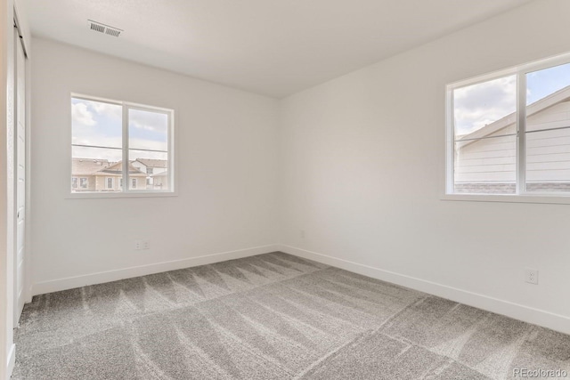 carpeted empty room featuring visible vents and baseboards