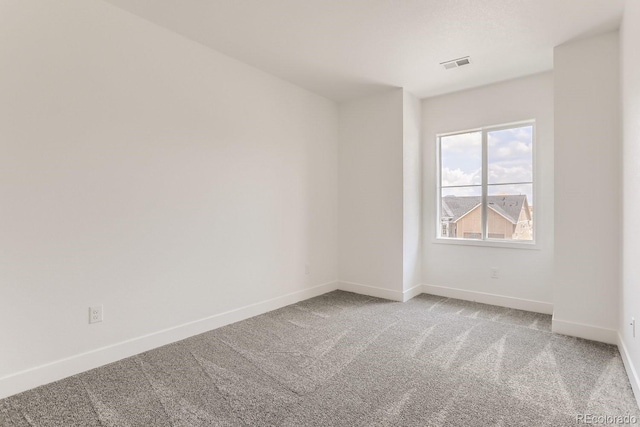 carpeted spare room with visible vents and baseboards