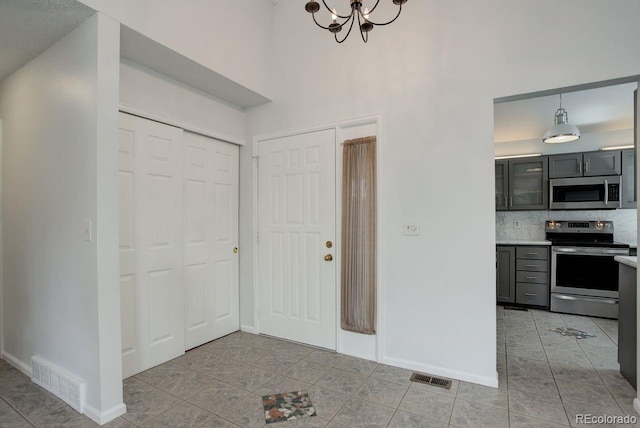 11186 E Baltic Dr, Aurora, CO 80014 - foyer entrance featuring light tile patterned flooring, baseboards, a chandelier, and a high ceiling