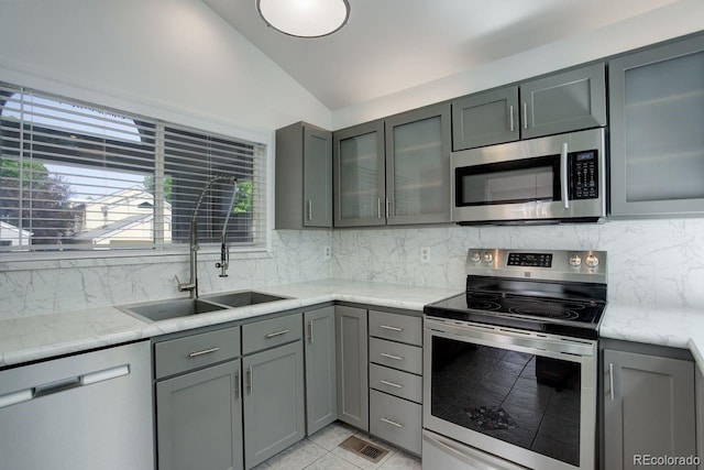 11186 E Baltic Dr, Aurora, CO 80014 - kitchen with appliances with stainless steel finishes, gray cabinetry, vaulted ceiling, a sink, and plenty of natural light