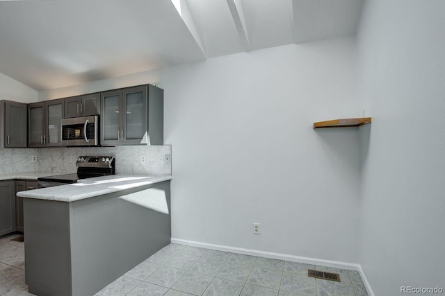 11186 E Baltic Dr, Aurora, CO 80014 - kitchen featuring appliances with stainless steel finishes, glass insert cabinets, vaulted ceiling, tasteful backsplash, and a peninsula