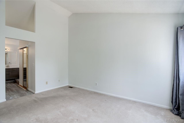 11186 E Baltic Dr, Aurora, CO 80014 - unfurnished bedroom with light colored carpet, baseboards, high vaulted ceiling, and ensuite bath