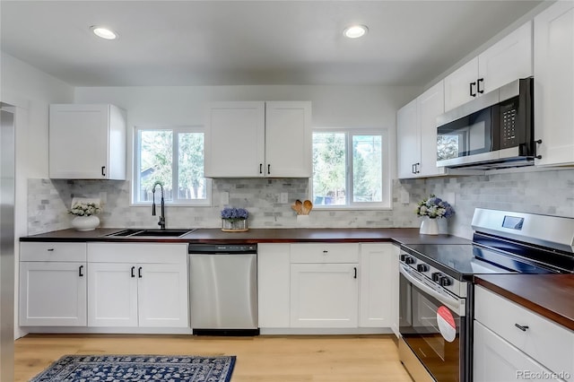 kitchen with sink, stainless steel appliances, plenty of natural light, and light wood-type flooring