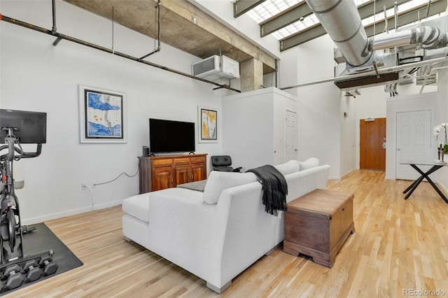 living room featuring wood finished floors, a towering ceiling, and baseboards