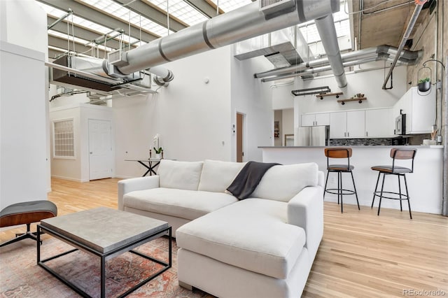 living area featuring light wood finished floors and a high ceiling