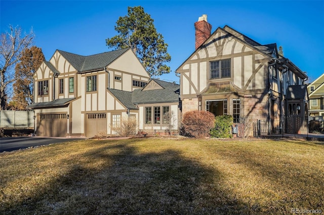 tudor home featuring an attached garage, fence, aphalt driveway, and stucco siding