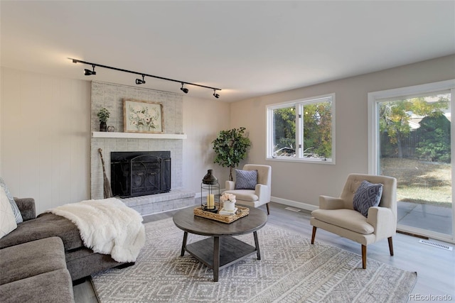 living room featuring hardwood / wood-style floors, rail lighting, and a brick fireplace