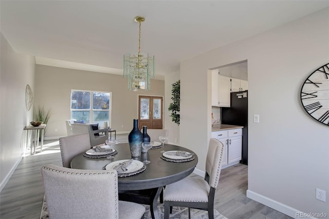 dining space with a chandelier, french doors, and light wood-type flooring