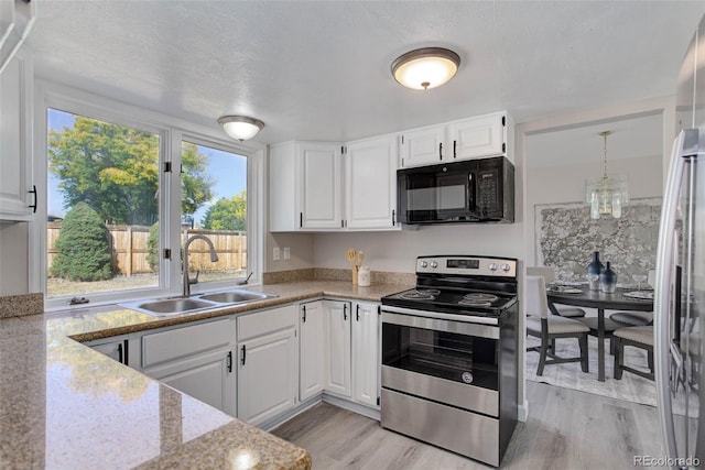 kitchen featuring a textured ceiling, stainless steel appliances, sink, white cabinets, and light hardwood / wood-style floors