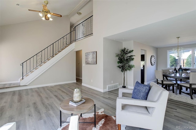 living room with hardwood / wood-style floors and ceiling fan with notable chandelier