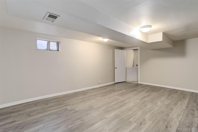 basement with light hardwood / wood-style floors and a textured ceiling