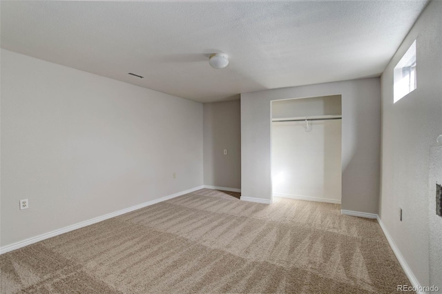 unfurnished bedroom with light colored carpet, a textured ceiling, and a closet