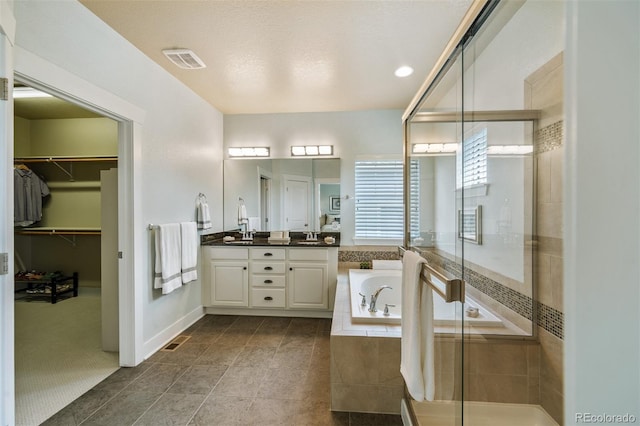 817 Uinta Way, Denver, CO 80230 - bathroom featuring a garden tub, double vanity, a stall shower, a walk in closet, and tile patterned flooring