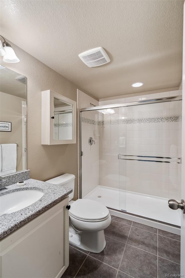 817 Uinta Way, Denver, CO 80230 - bathroom with a textured ceiling, toilet, vanity, a stall shower, and tile patterned floors