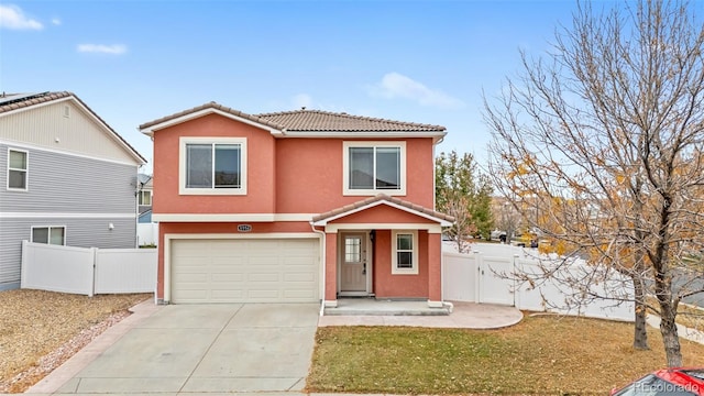 traditional home featuring an attached garage, a tiled roof, concrete driveway, stucco siding, and a gate