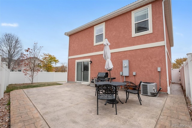 back of house with central AC unit, stucco siding, and a patio