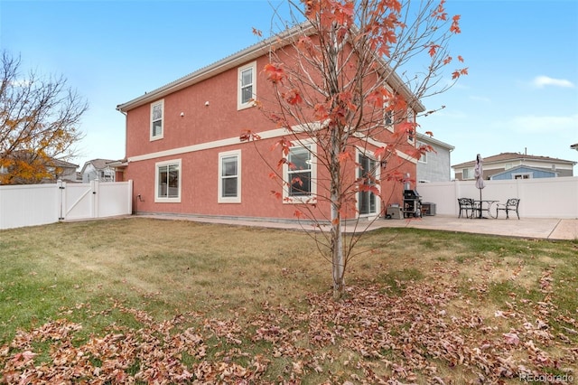 back of house featuring a gate, a patio area, and stucco siding