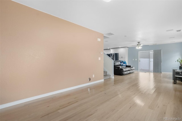 living area featuring light wood-type flooring, stairs, ceiling fan, and baseboards