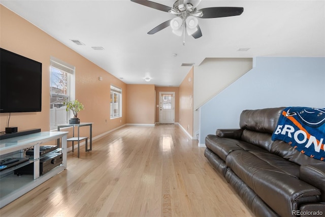 living area with light wood-style flooring, baseboards, and ceiling fan
