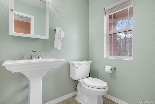 half bathroom featuring toilet and baseboards