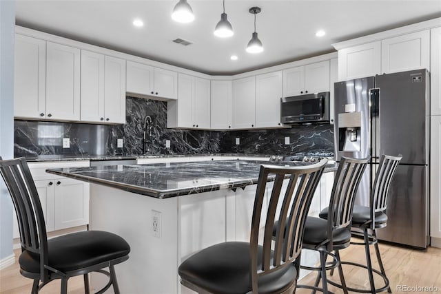 kitchen with hanging light fixtures, white cabinets, light hardwood / wood-style flooring, and appliances with stainless steel finishes