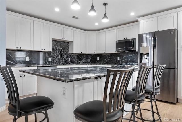 kitchen with stainless steel appliances, light wood-style floors, a breakfast bar, a sink, and recessed lighting