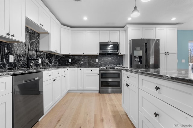 kitchen featuring stainless steel appliances, white cabinets, light hardwood / wood-style flooring, and backsplash