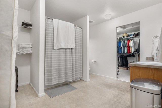 full bath with toilet, a shower with curtain, vanity, and baseboards