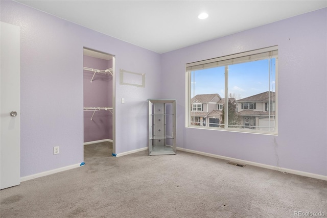 unfurnished bedroom featuring carpet, baseboards, and a walk in closet