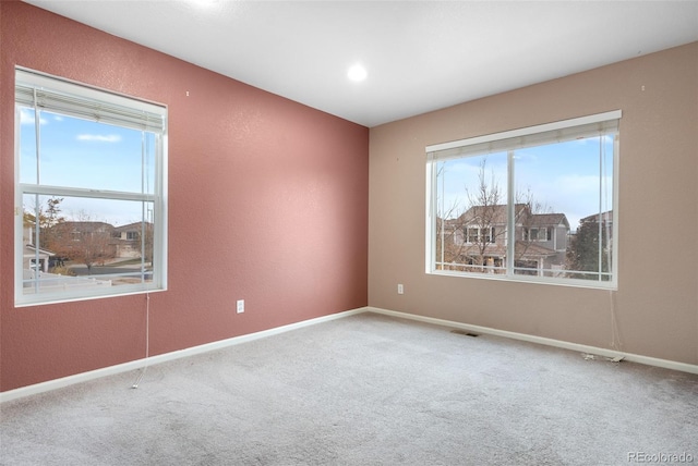 empty room with carpet floors, baseboards, and a textured wall