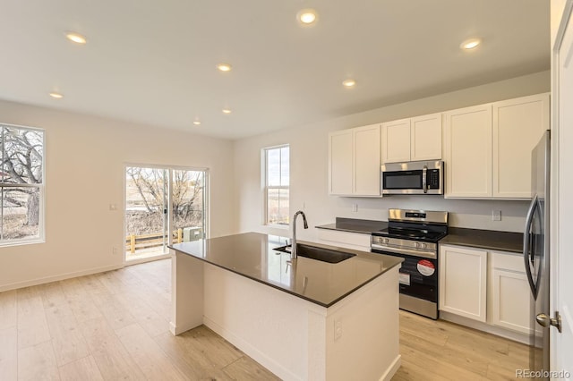 kitchen with a center island with sink, white cabinets, sink, and appliances with stainless steel finishes