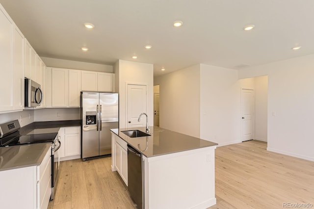 kitchen with white cabinets, sink, light hardwood / wood-style flooring, an island with sink, and stainless steel appliances