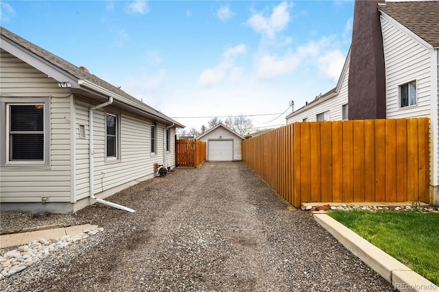 view of side of home with an outdoor structure, a garage, fence, and gravel driveway