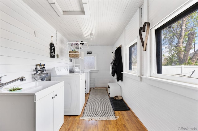 washroom with light wood finished floors, cabinet space, and washer and clothes dryer
