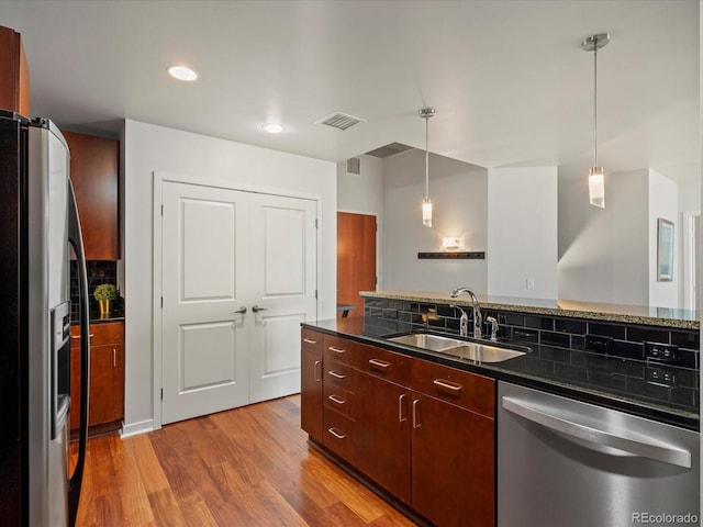 kitchen featuring pendant lighting, sink, decorative backsplash, appliances with stainless steel finishes, and wood-type flooring