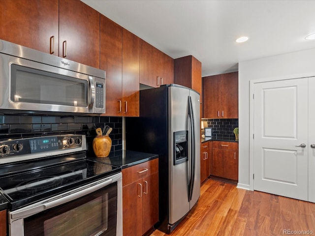 kitchen with backsplash, light wood-type flooring, and stainless steel appliances