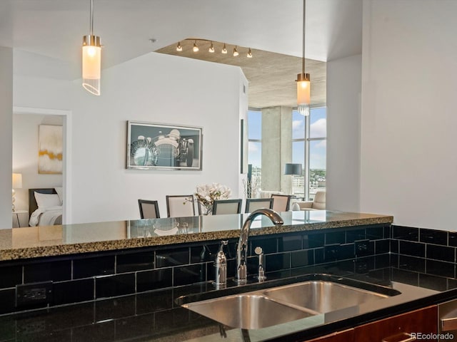 kitchen with pendant lighting, dark stone countertops, and sink