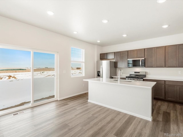 kitchen featuring hardwood / wood-style floors, an island with sink, stainless steel appliances, and sink