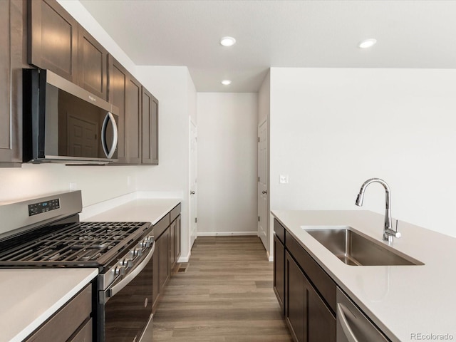 kitchen with sink, light hardwood / wood-style floors, stainless steel appliances, and dark brown cabinetry