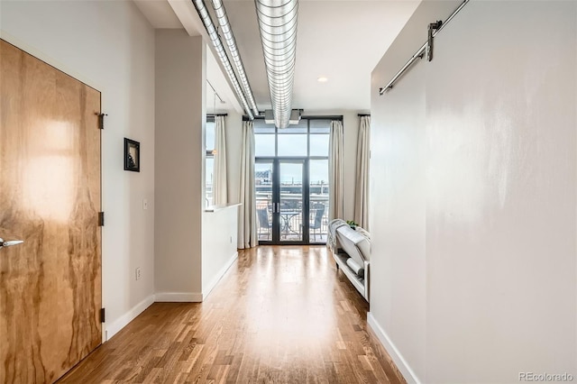 corridor featuring french doors, wood finished floors, and baseboards