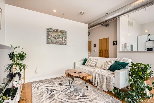 living room featuring wood finished floors, visible vents, and baseboards