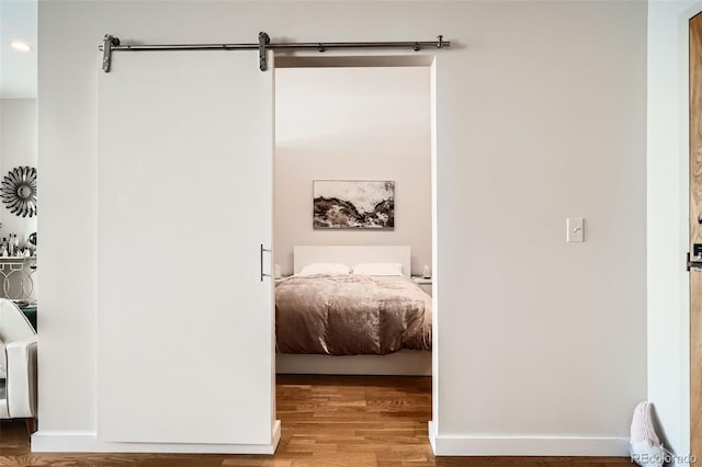 bedroom with light wood-style flooring, baseboards, and a barn door