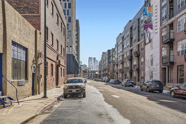 view of road with sidewalks, a city view, and curbs